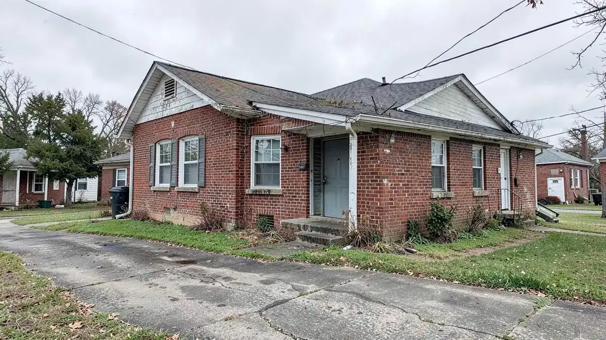 Older brick rental duplex with a shared driveway in a North Mississippi town